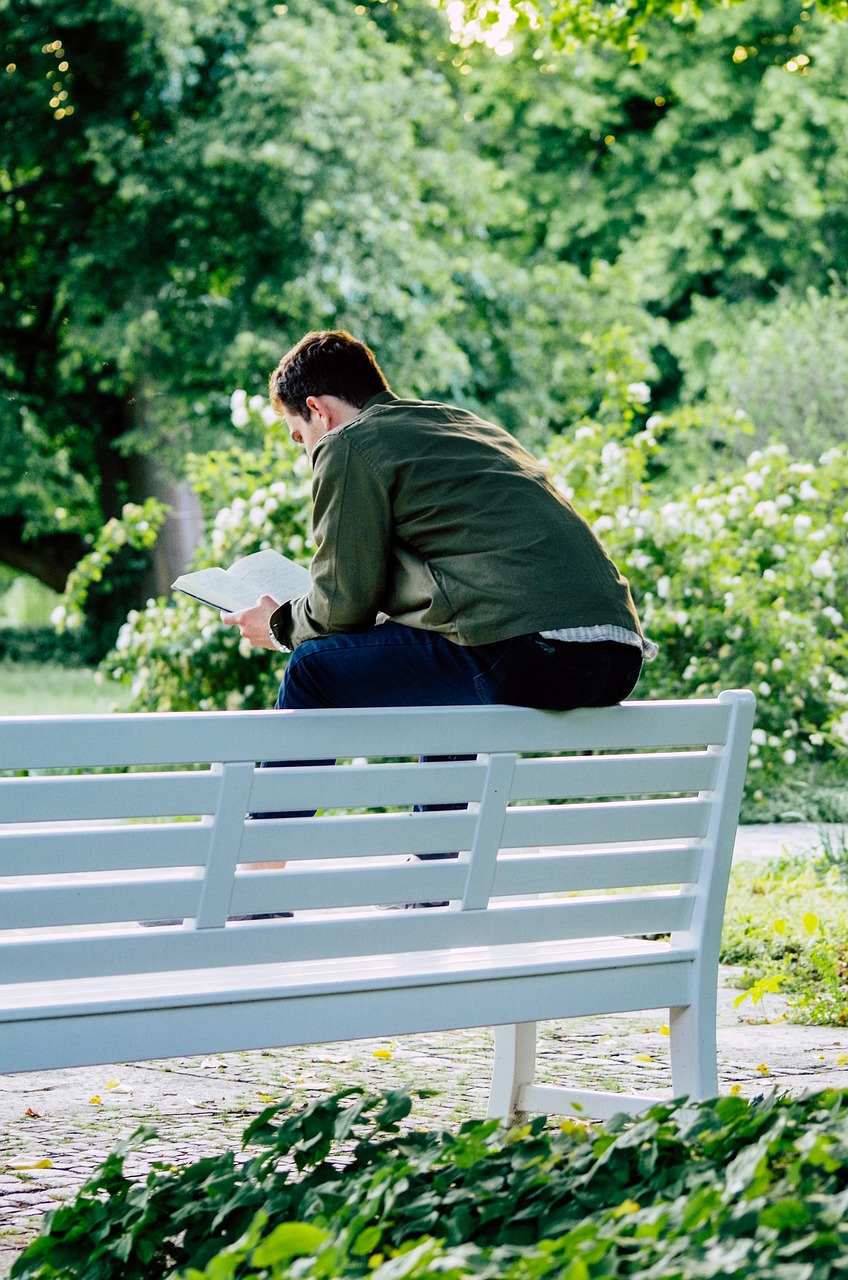 Young adult sitting on bench reading