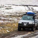 An SUV driving off-road with gear secured on top, representing the "Best Bug Out Vehicles"