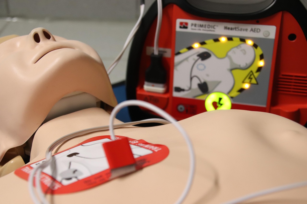 A CPR training dummy with a defib attached, representing CPR and Basic First Aid What Every Prepper Should Know