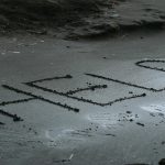 "HELP" written in the sand, representing Emergency Signaling