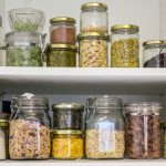 Stocked pantry shelves with glass containers filled with different foods, representing How to Create a 3-Month Emergency Food Supply