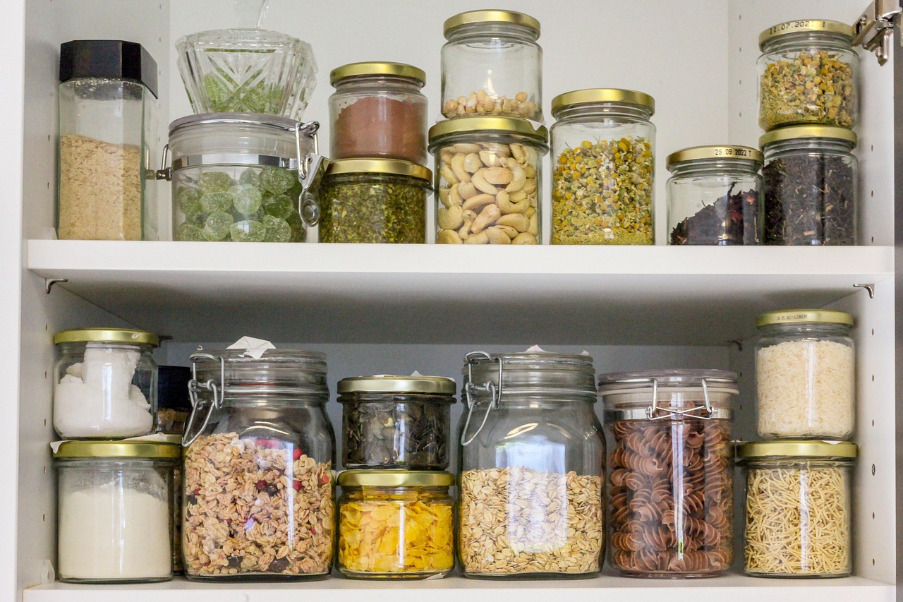 Stocked pantry shelves with glass containers filled with different foods, representing How to Create a 3-Month Emergency Food Supply