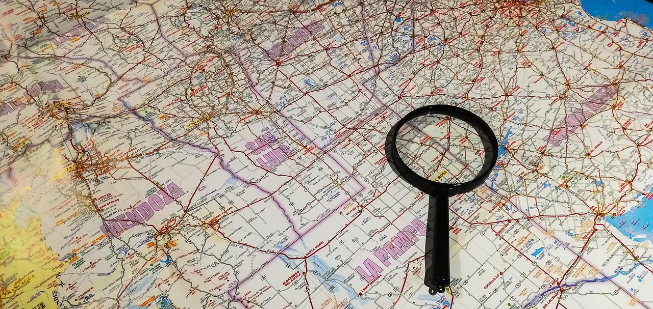 Magnifying glass on top of a map, representing "Top 5 Mistakes in Bug Out Route Planning"